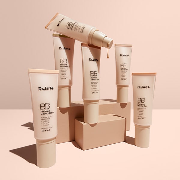 Six bottles of Dr.Jart+'s Premium BB Tinted Moisturizer with SPF 40 lean against peach backdrop