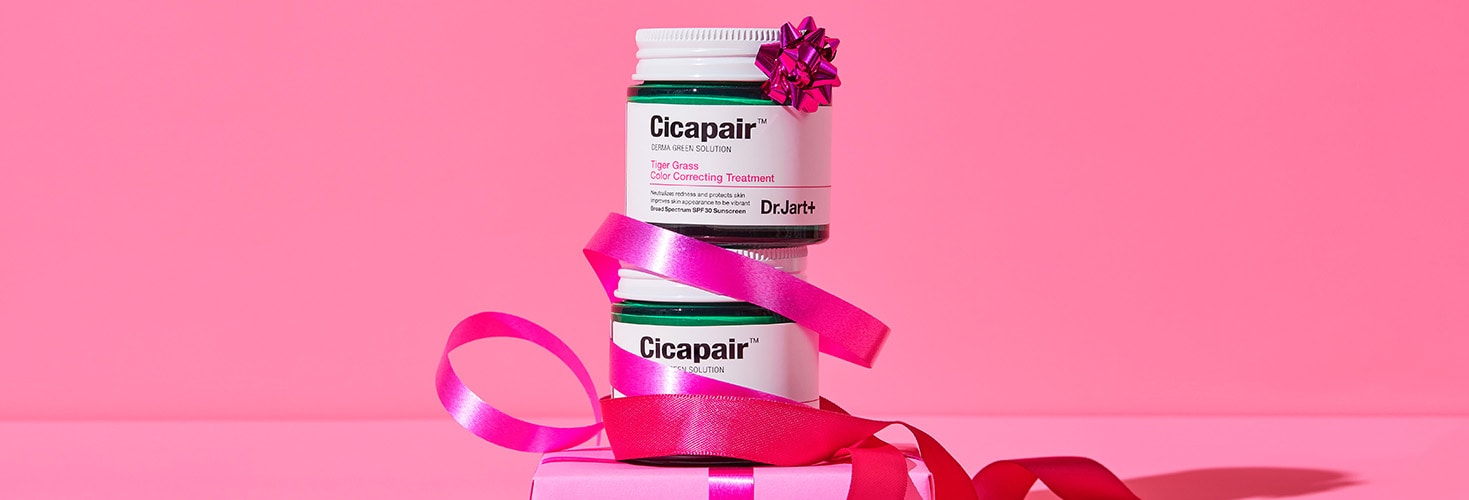 Jars of Dr.Jart+'s Cicapair Color Corrector treatment are stacked and twisted among festive pink ribbons.