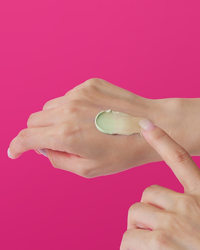 Texture swipe of Cicapair green to beige color correcting cream on the back of hand.