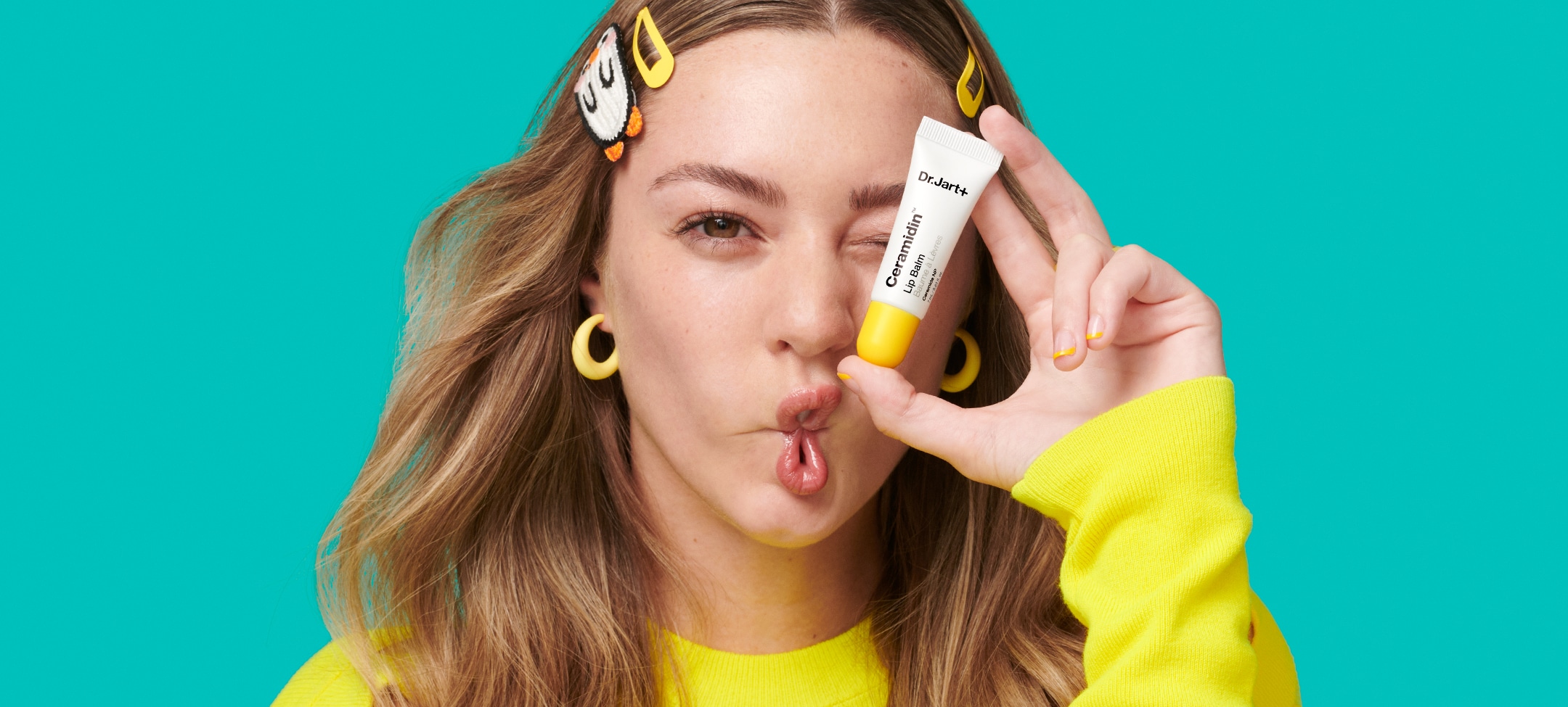 Woman holds up tube of Ceramidin Lip Balm