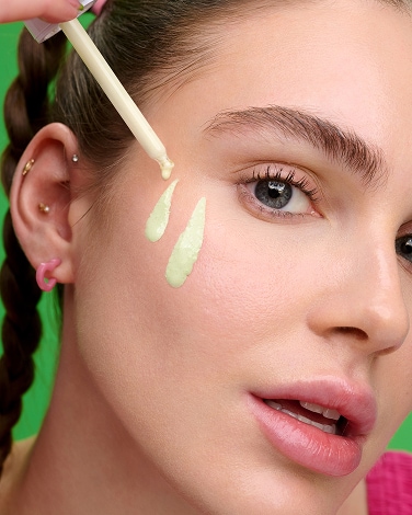 Two bottles of Premium BB Tinted Moisturizer are on a dark background showcasing the shade range thru the textures.