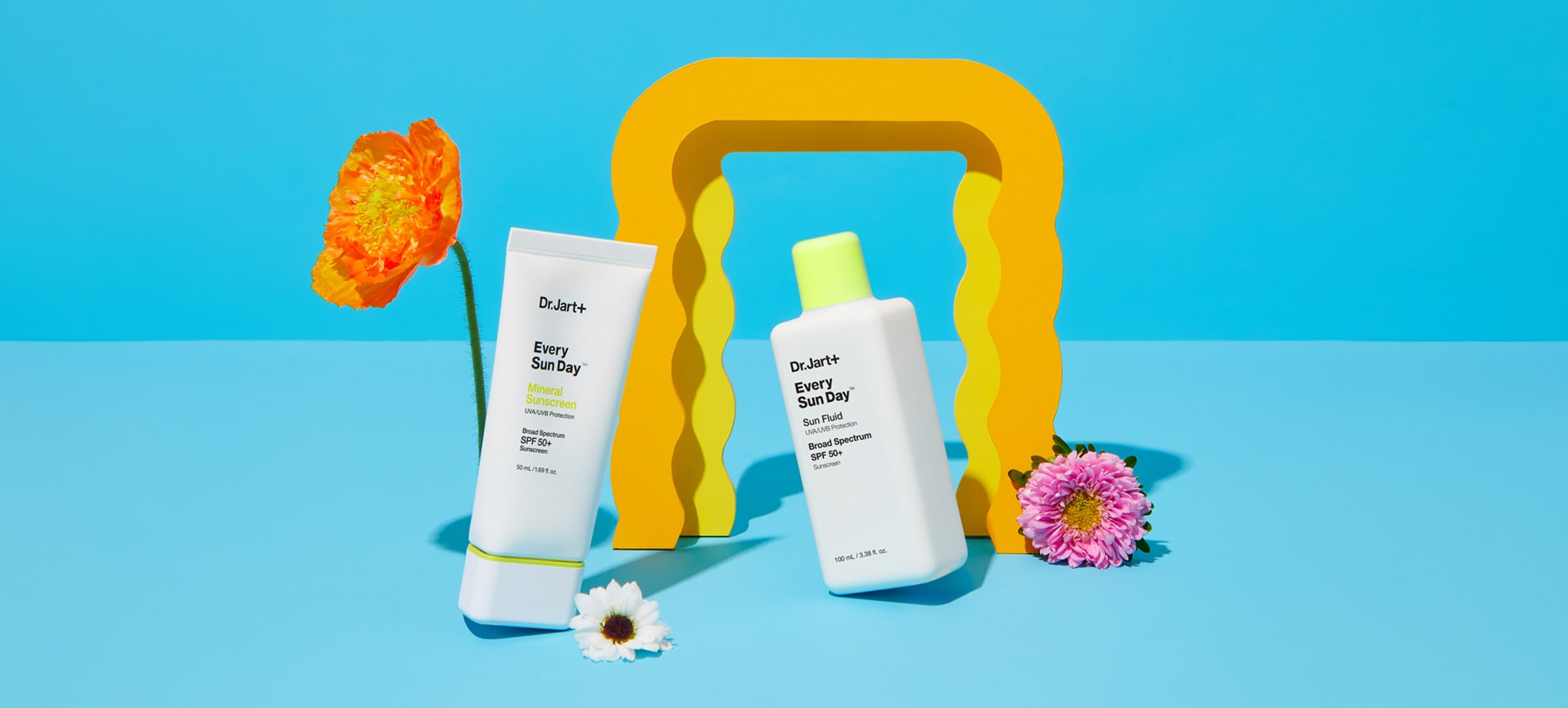 Every Sun Day Mineral Sunscreen and Fluid Sunscreen bottles on bright background with summer themed artistic elements