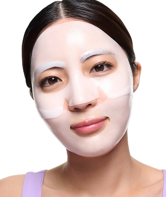 A model smiles while applying pumps of cleanser to her cheek area 