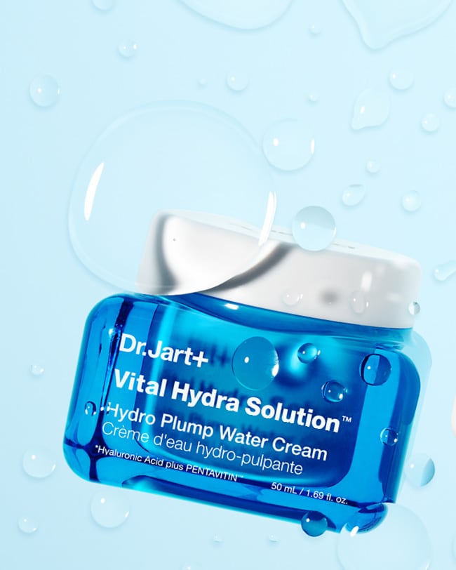 Vital Hydra Solution Face Cream jar is displayed amongst water droplets to showcase hydrating properties.