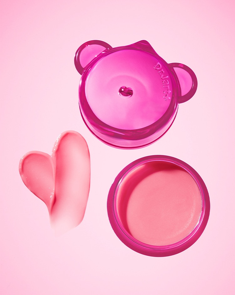 Open jar of the pink jelly bear is displayed on a light pink background with a texture swirl in the shape of a heart.