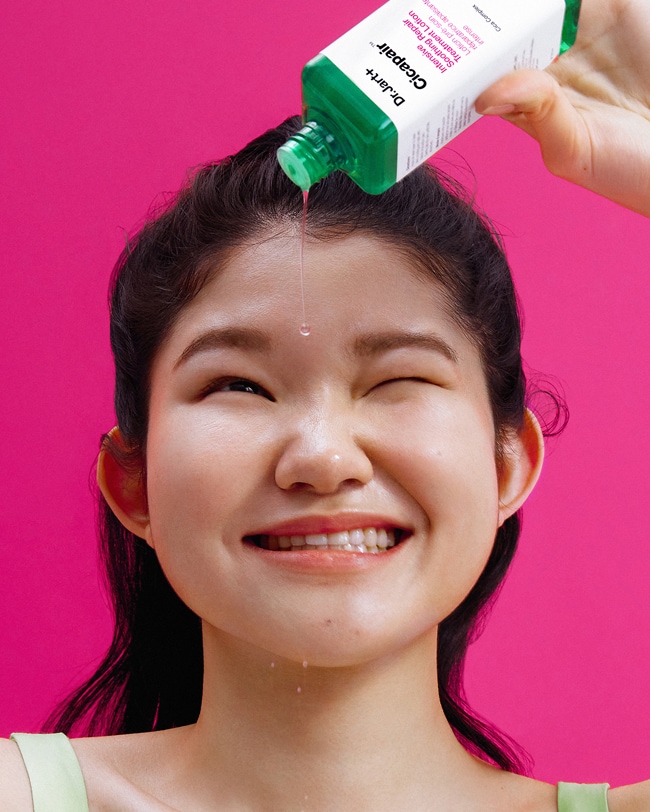 Woman squeezes Cicapair Cream onto hand and smooths across face and skin.