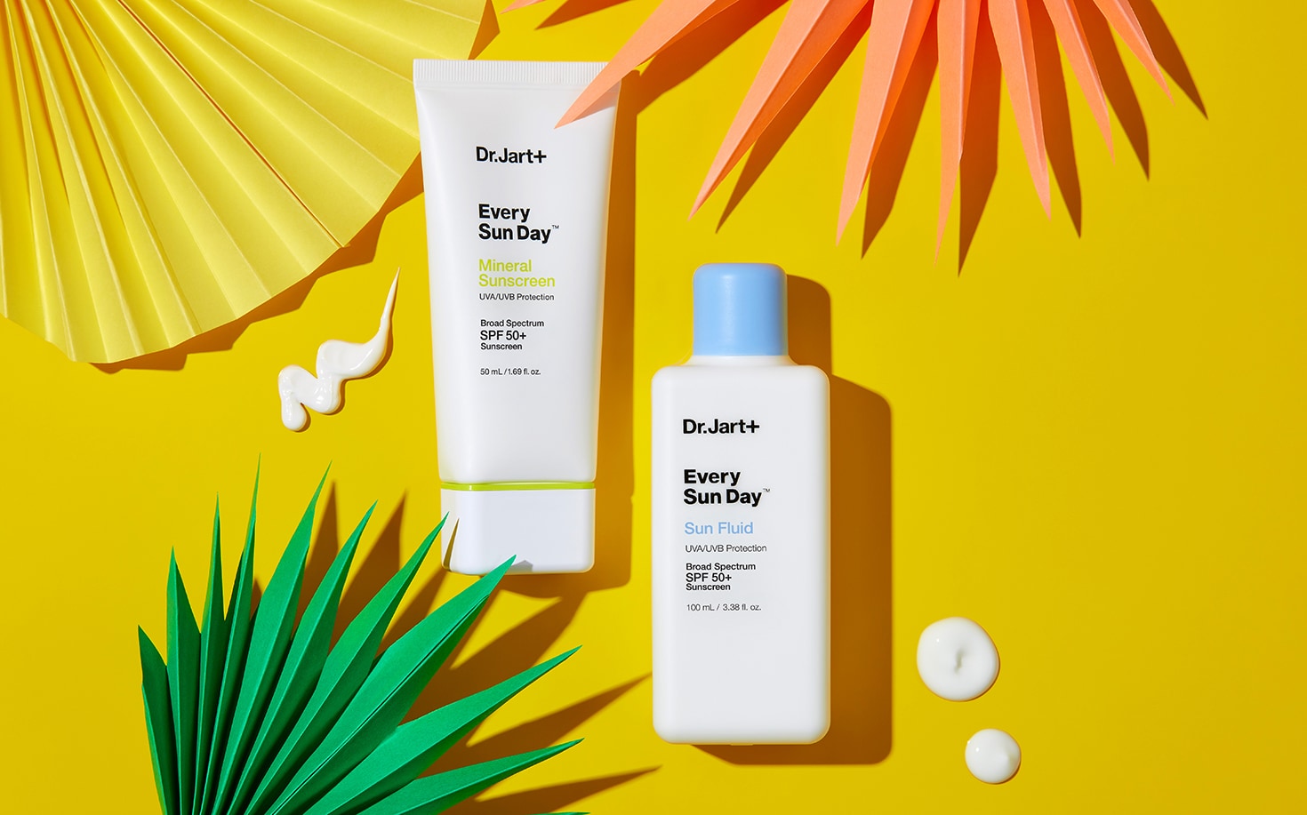 Every Sun Day Mineral Sunscreen & Fluid Sunscreen bottles on bright, sunny tropical background with dollops of sunscreen texture